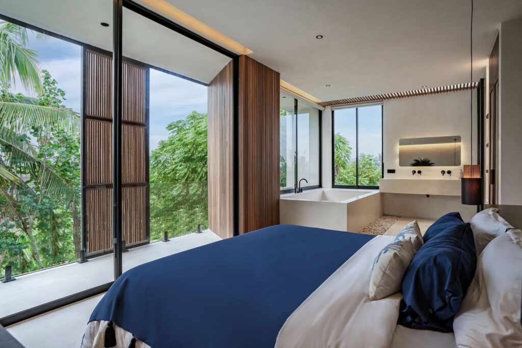 Master bedroom at Villa Amore in Bereban Bali with floor-to-ceiling windows and tropical greenery views